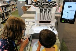 kids watching embroidery machine