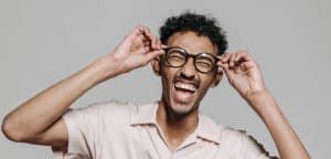 man holding his glasses laughing